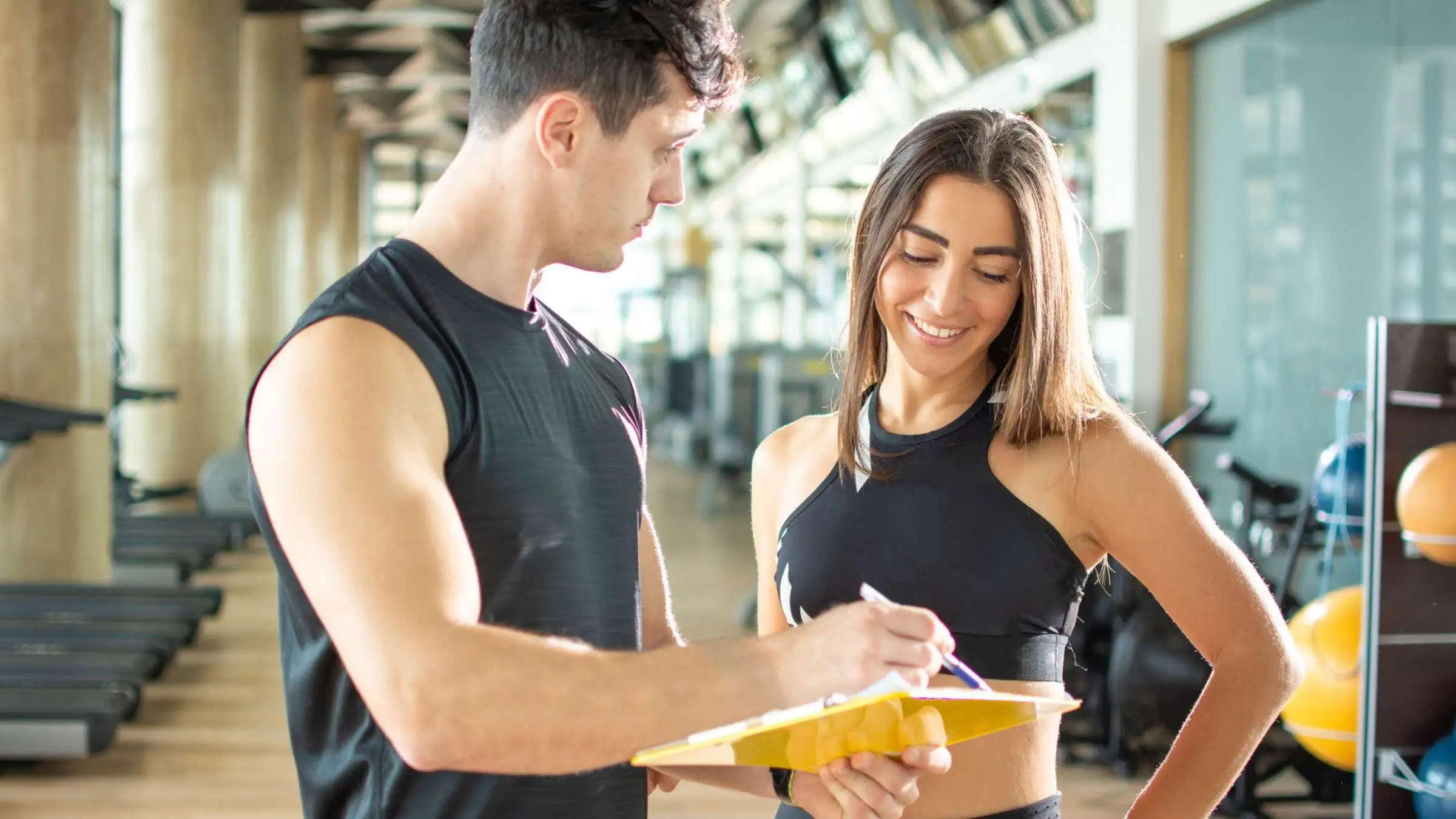 A trainer and client discussing a workout plan on a tablet